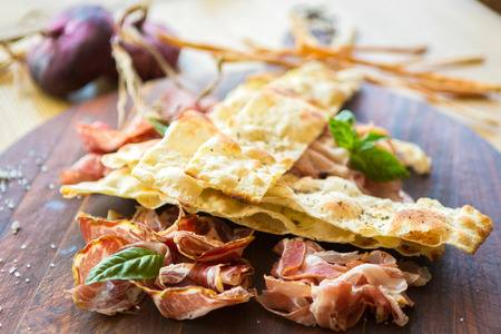 HomemHomemade prosciutto and basil on a wooden board in the Italian styleade prosciutto and basil on...