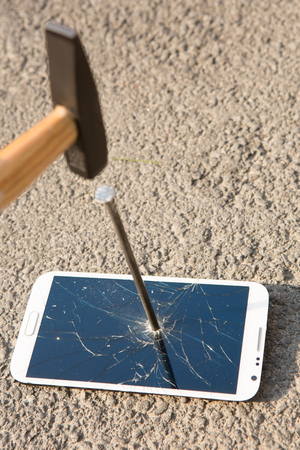 hammer smashing the screen of a handheld electronic deviceの写真素材