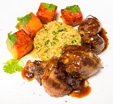Organic meat of lamb cooked with slices of pumpkin and quinoa in oriental style on a white plateの写真素材