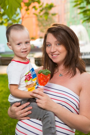Laughing young pregnant mother playing with her two year old son in a beautiful gardenの写真素材