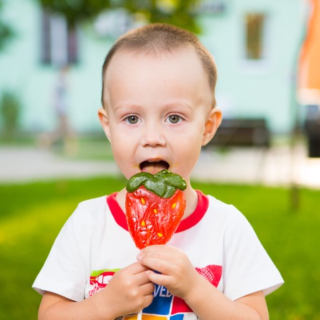 Boy with large lollipop in the parkの写真素材
