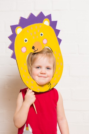 Little blonde girls holding hedgehog mask on white backgroundの写真素材