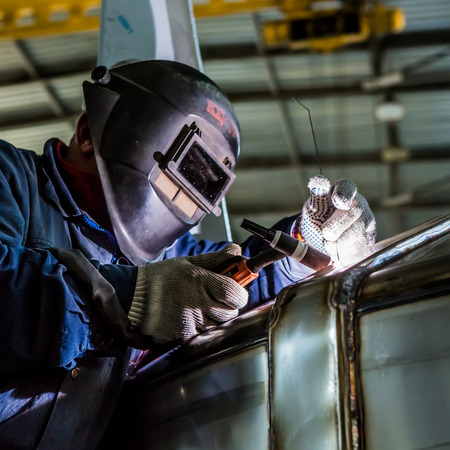 Man welding with reflection of sparks on visor. Hard job. Construction and manufacturingの写真素材