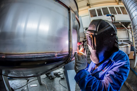 Man welding with reflection of sparks on visor. Hard job. Construction and manufacturingの写真素材