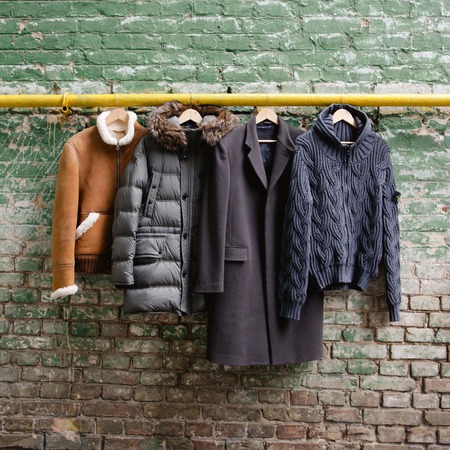 Men&amp;#39;s trendy clothing on hangers on grunge brick wall. Concept background