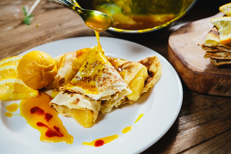 Dessert - stuffed pancakes with orange syrup and orange ice-creamの写真素材
