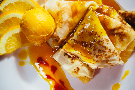 Dessert - stuffed pancakes with orange syrup and orange ice-creamの写真素材