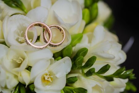 Two wedding rings in infinity sign with bouquet on black background. Love concept.の写真素材