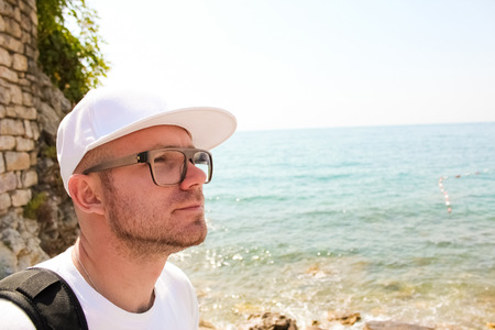 Handsome young man against bright beach backgroundの写真素材