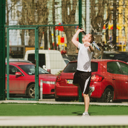 young man play tennis outdoor on tennis field at early morningの写真素材
