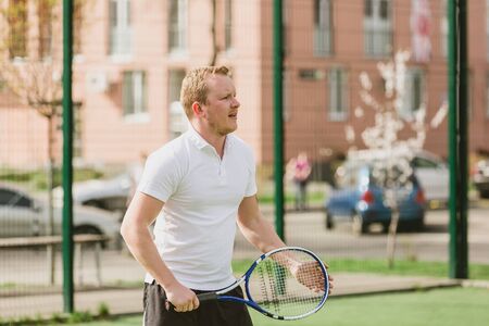 young man play tennis outdoor on tennis field at early morningの写真素材