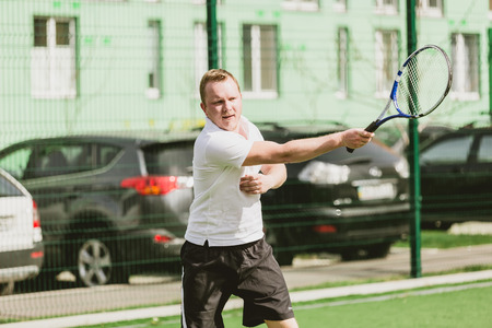 young man play tennis outdoor on tennis field at early morningの写真素材