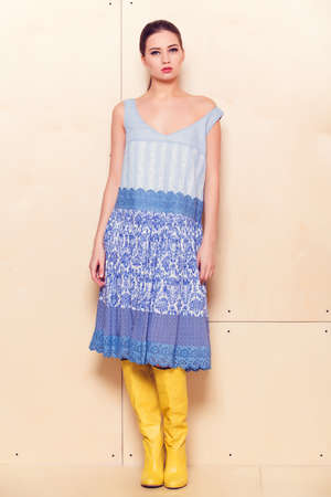 Full body slim woman in blue sundress on wooden backgroundの写真素材