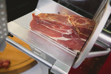 Waiter is slicing prosciutto in restaurant, toned imageの写真素材