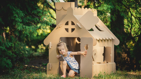girl playing cardboard house in a city park on a sunny dayの写真素材