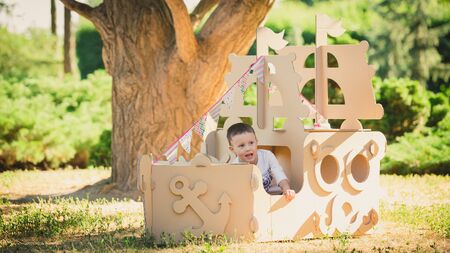 Boy playing in a cardboard boat in the park. Eco conceptの写真素材