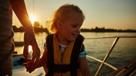 Little girl enjoying ride on yacht at sunsetの写真素材
