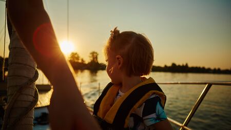 Little girl enjoying ride on yacht at sunsetの写真素材