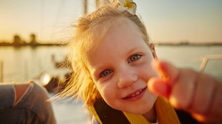 Little girl enjoying ride on yacht at sunsetの写真素材