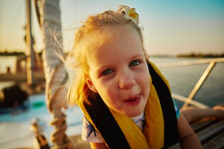 Little girl enjoying ride on yacht at sunsetの写真素材