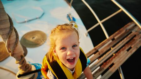 Little girl enjoying ride on yacht at sunsetの写真素材