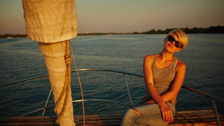Woman traveling by boat at sunset among the riverの写真素材