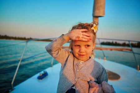 Little girl enjoying ride on yacht at sunsetの写真素材