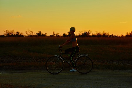 Biker girl at the sunset on the meadowの写真素材