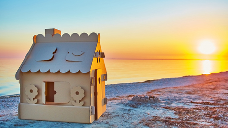 Toy house made of corrugated cardboard in the sea coast at sunset. The concept of eco-estateの写真素材