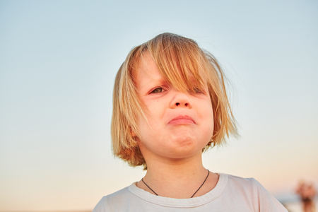Beautiful sad little girl crying, on sunset background.の写真素材