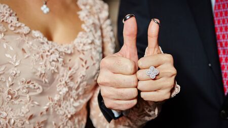 The wedding rings on fingers painted with the bride and groom