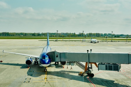 Airplane at the terminal gate ready for takeoff - Modern international airport during sunset -...