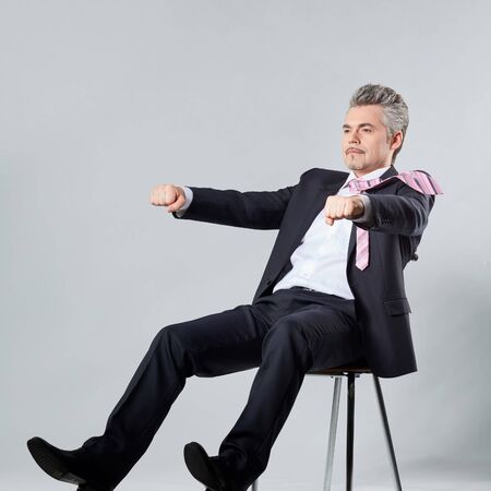 businessman in a luxury suit is riding on an imaginary motorcycle. The concept of rest or trevelの写真素材