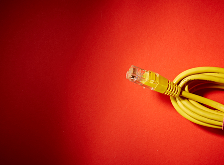 The yellow network cable on red backgroundの写真素材
