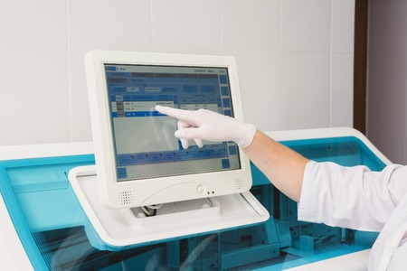 Lab tech loading samples into a chemistry analyzer in clinicの写真素材
