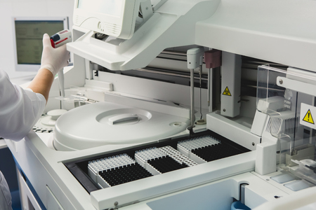 Lab tech loading samples into a chemistry analyzer in clinicの写真素材