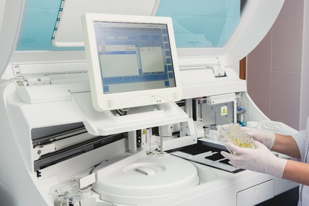 Lab tech loading samples into a chemistry analyzer in clinicの写真素材