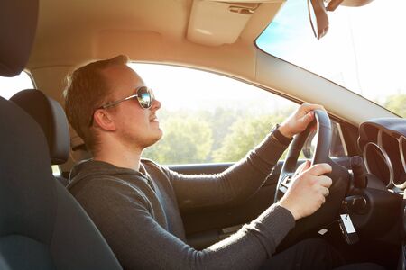 Handsome man driving luxury car wearing  sunglasses with retro filter effect