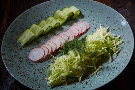 Fresh spring light vegetarian salad with cucumber and radish and greens on a wooden background. The top view.の写真素材