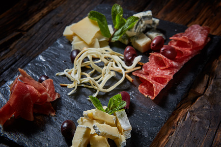 Salami and cheese platter with vegetable and herbsの写真素材