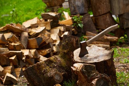 Old ax on a log and firewood in the backgroundの写真素材