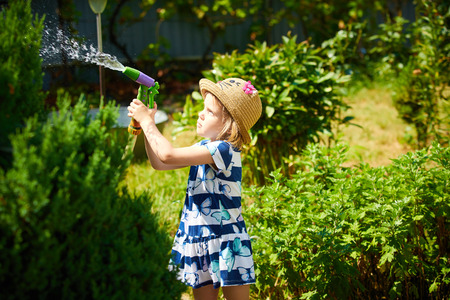 Little happy girl watering garden. Summer dayの写真素材