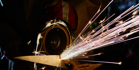 Worker cutting metal with grinder. Sparks while grinding iron.の写真素材