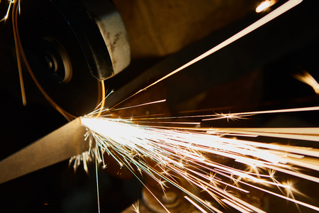 Worker cutting metal with grinder. Sparks while grinding iron.