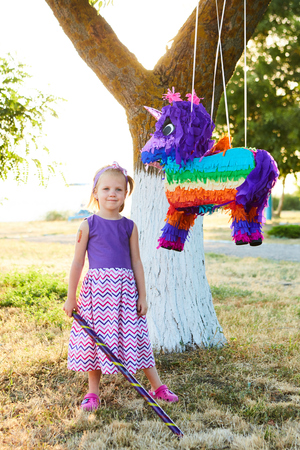 Young girl at an outdoor party hitting a pinata. Celebrating a birthdayの写真素材