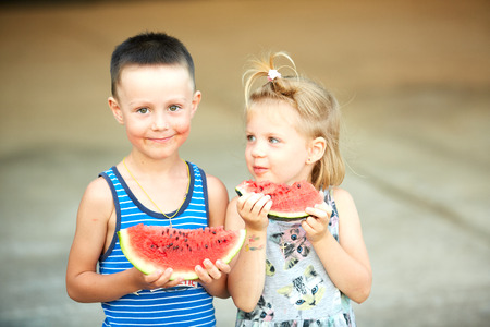 Little girl and boy with a piece of watermelon in handsの写真素材