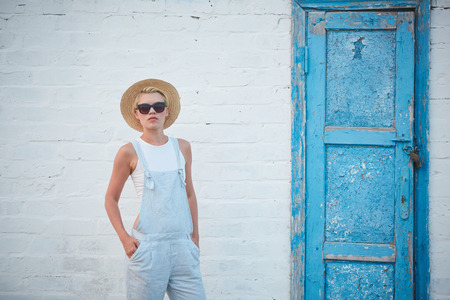 Pretty slim tan blonde stylish woman in straw hat and sunglasses posing.の写真素材