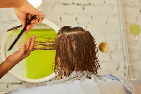 Hairdresser making a hair style to cute little girl.の写真素材
