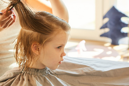 Hairdresser making a hair style to cute little girl.の写真素材