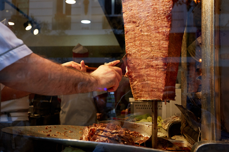 An arm moving to cut the kebab meatの写真素材